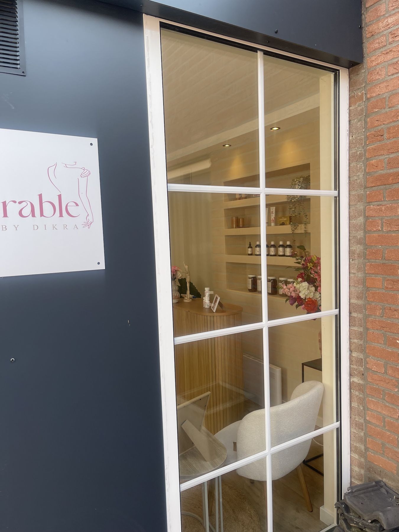 Het bord van Memorable By Dikra naast de glazen deur